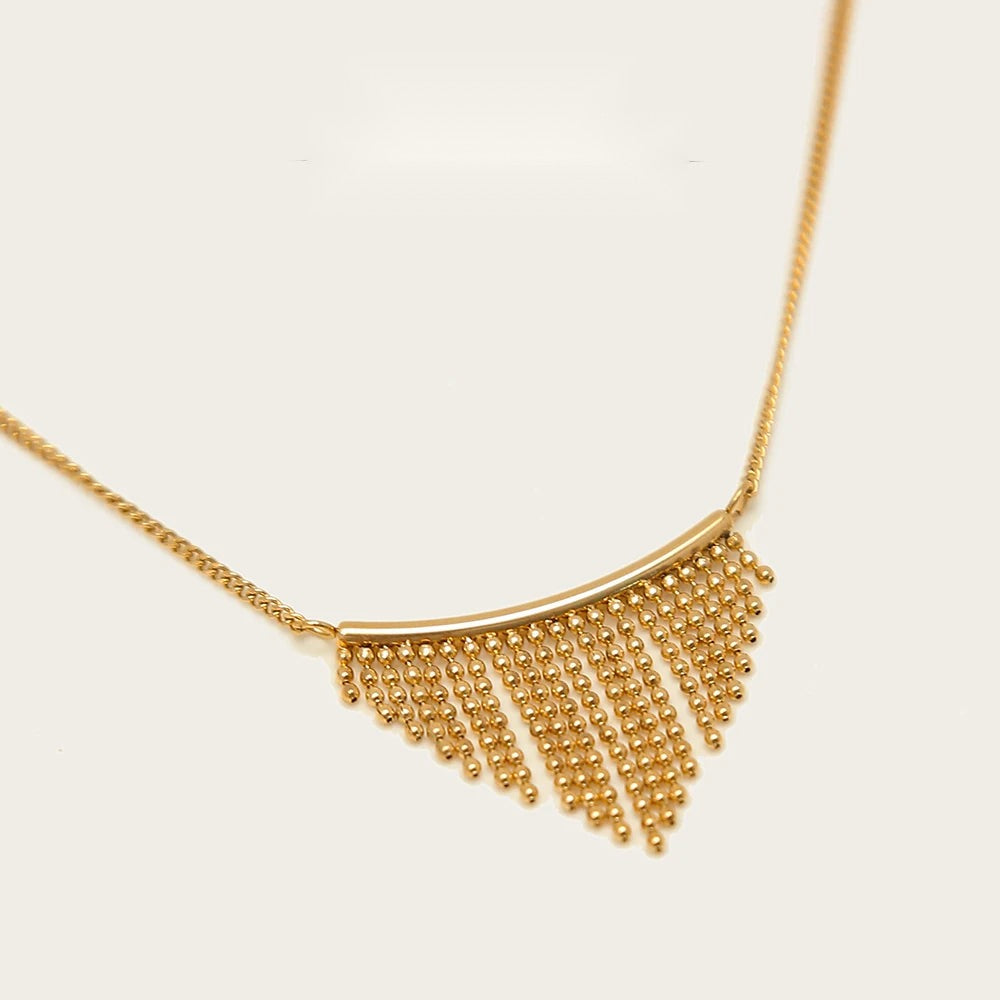 Gold chain necklace with a curved charm bar and fringe detail, an example of the chunky charm necklace trend