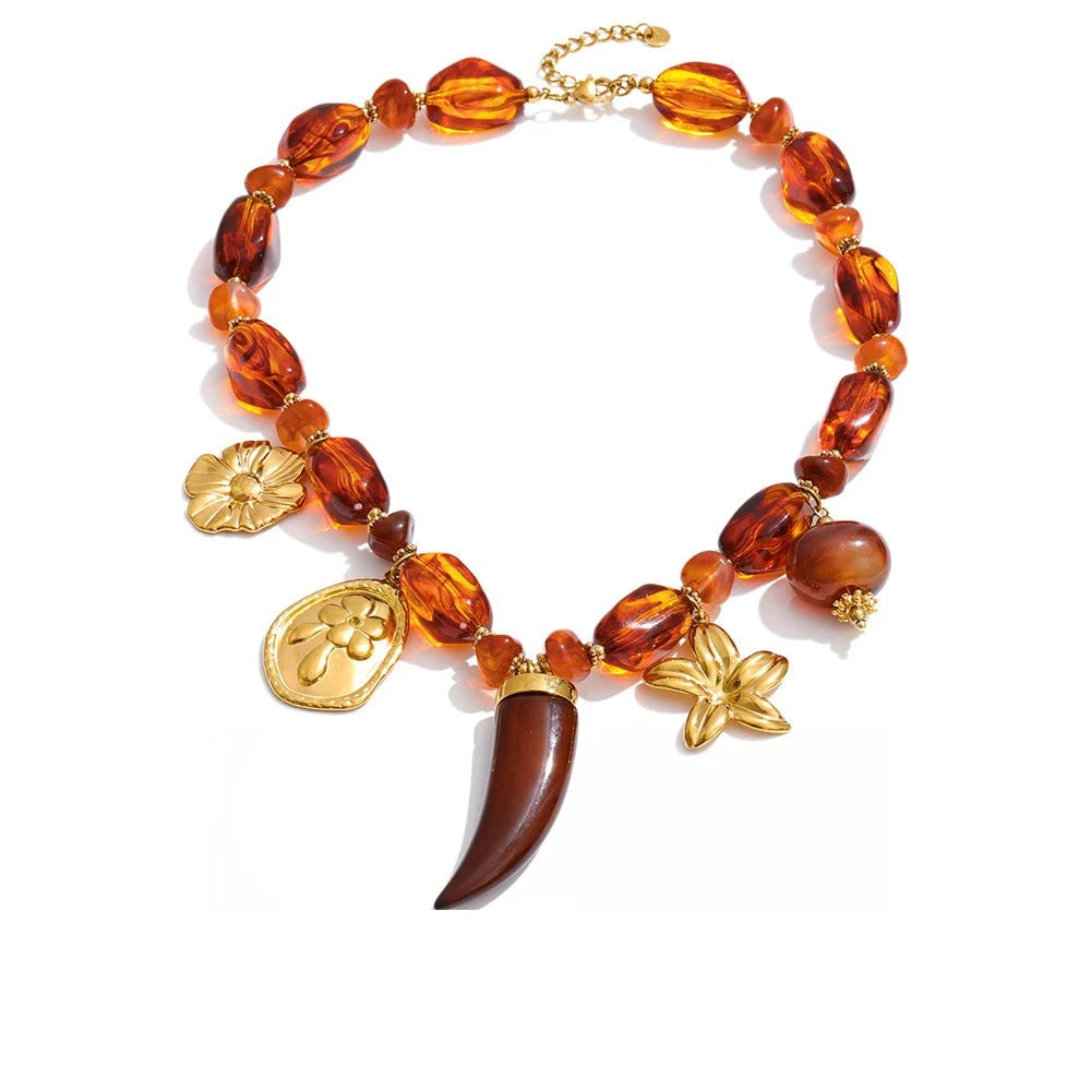 Gold-plated stainless steel necklace with resin, featuring a large red amberstone pendant and a small gold-plated charm shaped like a leaf.