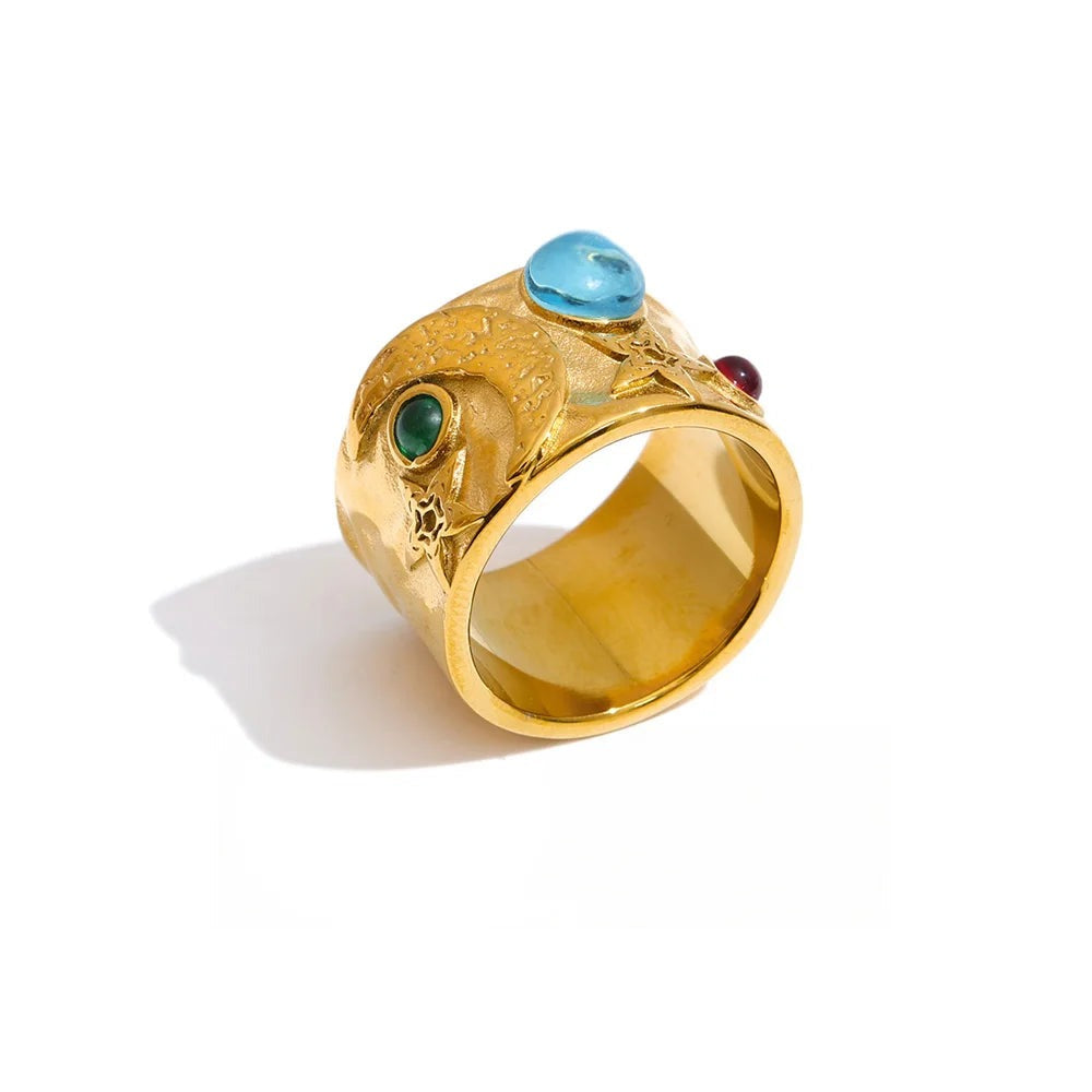 Gold-plated stainless steel ring with a large blue gemstone and a small red gemstone.