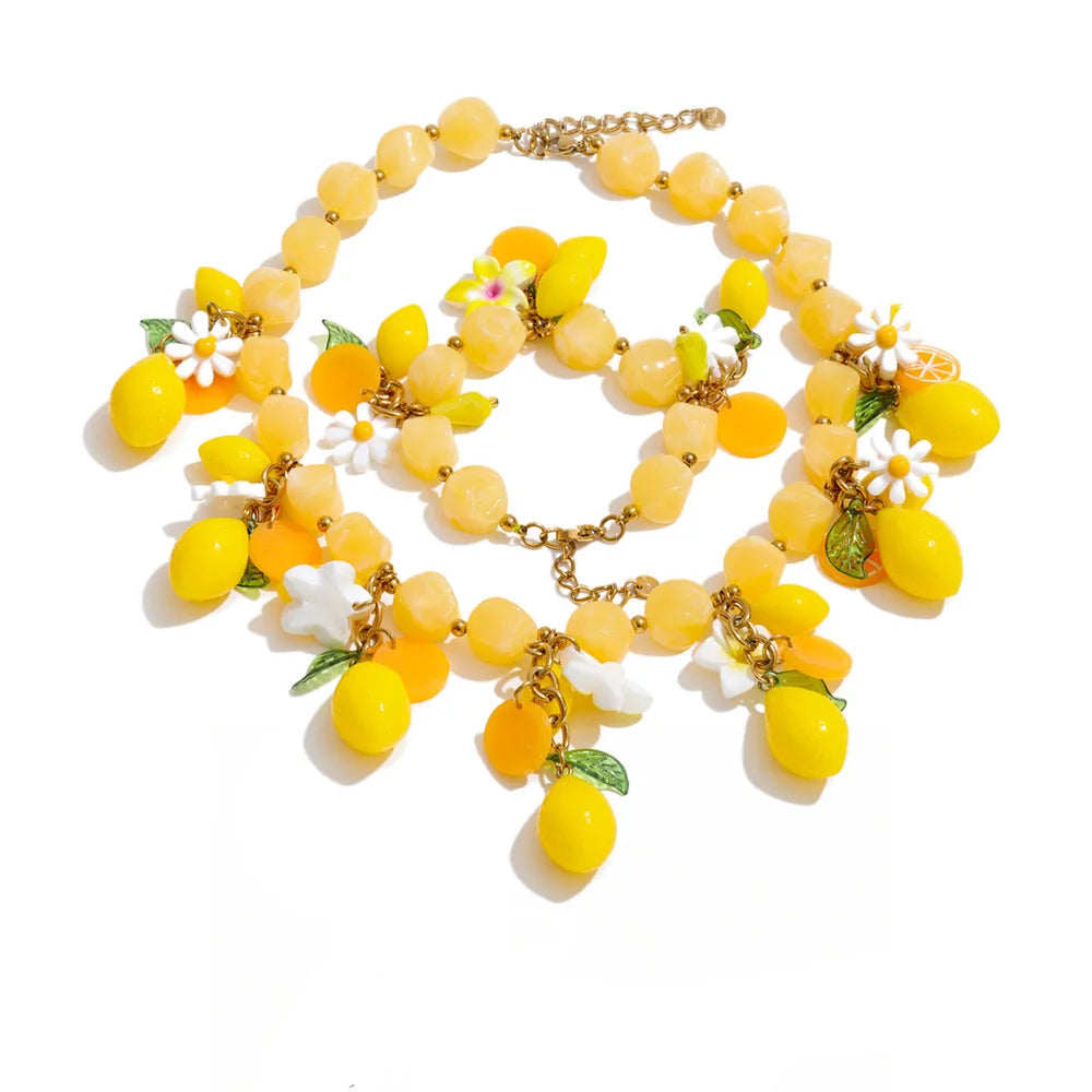 Gold-plated stainless steel necklace with resin beads featuring yellow fruit and white flowers.