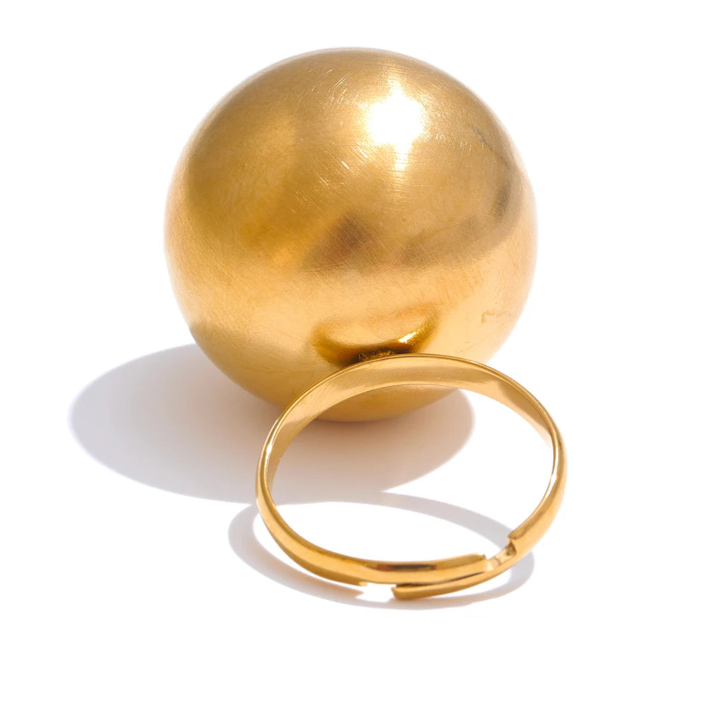 Gold-plated stainless steel ring with a large sphere in the background.