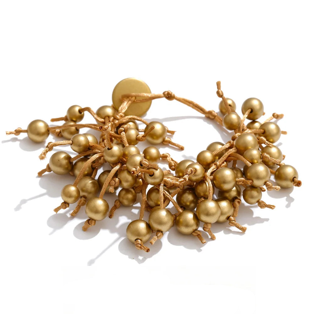 Bracelet made of resin, gold-toned finish, adorned with spherical beads.
