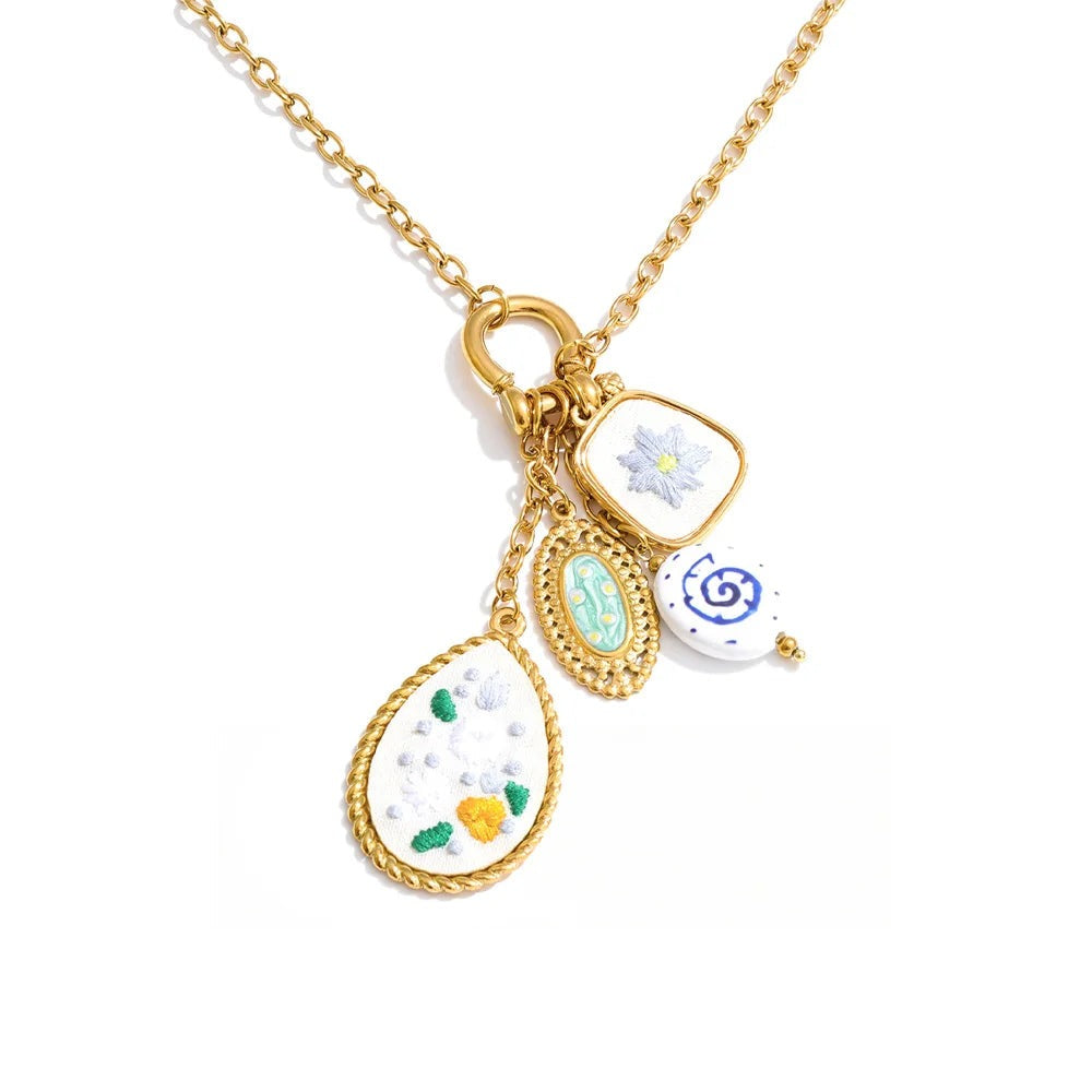 Gold-plated stainless steel necklace featuring a pendant with a floral design and various small decorative elements.