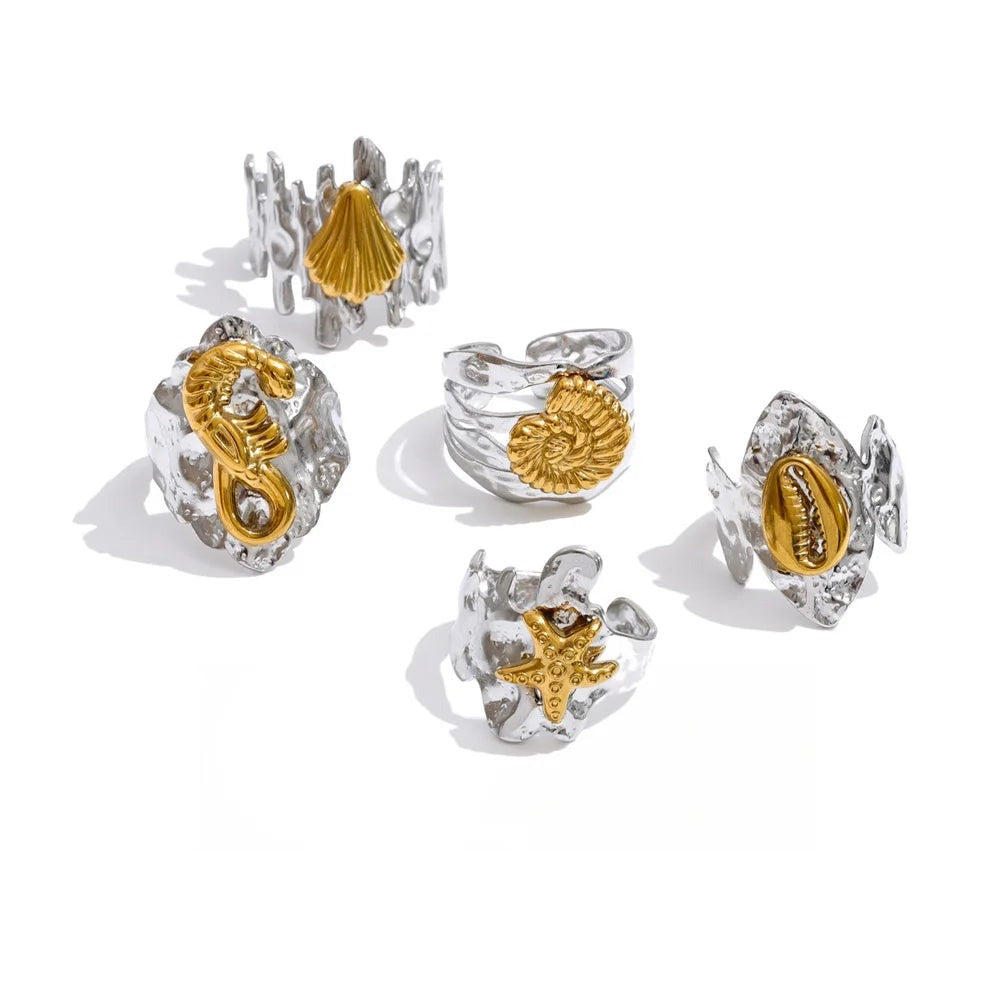 Silver ring set with shells and a snake charm.
